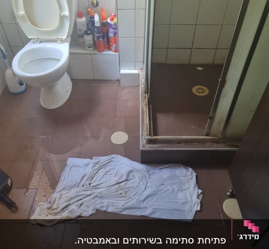 חדר אמבטיה עם רצפה רטובה ומגבת על הרצפה